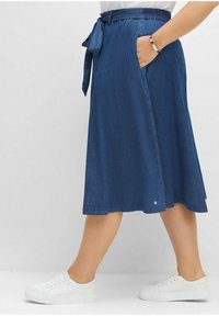 Tmavě modrá džínová sukně s páskem v pase, bočními kapsami a rozšířeným tvarem, s čistým lemem a minimálním množstvím kovových doplňků.