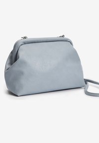 Borsa a mano di pelle blu chiaro con una texture morbida, forma arrotondata e una tracolla sottile. Presenta un gancio metallico e un design liscio e minimalista.