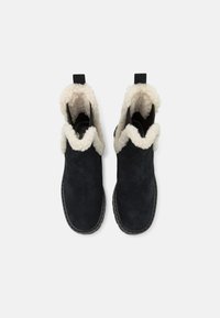 Black suede ankle boots with a cream faux fur lining, rounded toe, and black rubber sole. Features pull tabs for easy wear.