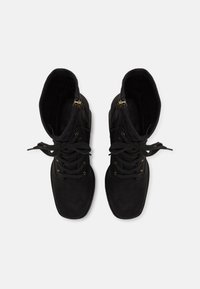 Bottes cheville en daim noir avec bouts ronds, lacets et fermetures éclair latérales ; dotées d'œillets en métal et de tissu textur é pour un détail supplémentaire.