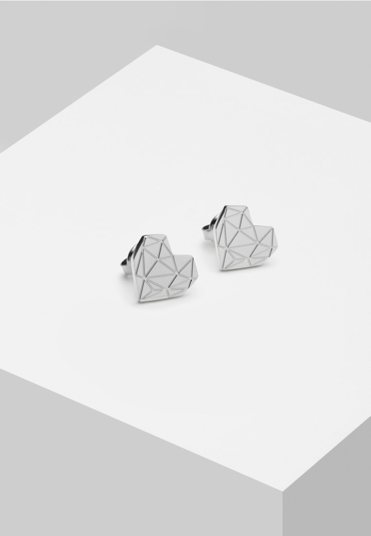 Silvergeometriska hjärtformade örhängen med ett mönstrat design. Slät metallisk yta med flera triangulära facetter.