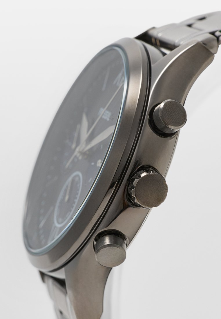 Reloj cronógrafo de metal con esfera negra, marcadores de hora plateados, tres botones pulsadores y una correa de plata texturizada.