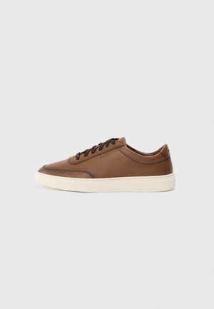 Baskets en cuir marron avec une finition lisse, à lacets et semelle en caoutchouc de couleur blanche cassée. Branding minimal sur le côté.