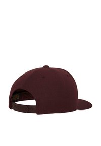 Tumeda snapback müts lapik äärega, tekstuuriga kangas, reguleeritav rihm taga ja väike logo silt siseküljel.