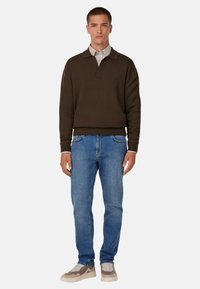 Pruun pikkade varrukatega pullover kaelusega, koos helesiniste teksade ja beežide tossudega. Igapäevane lõige ribaga mansettidega.