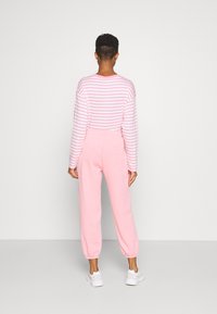 Striped long-sleeve top in pink and white, paired with pink sweatpants. Relaxed fit, elastic cuffs, and waistband. White sneakers complete the look.
