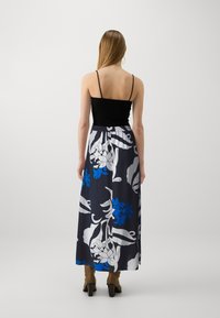 Top preto com alças, combinado com uma saia longa com padrão floral em azul-marinho, branco e azul, com uma confortável cintura elástica.