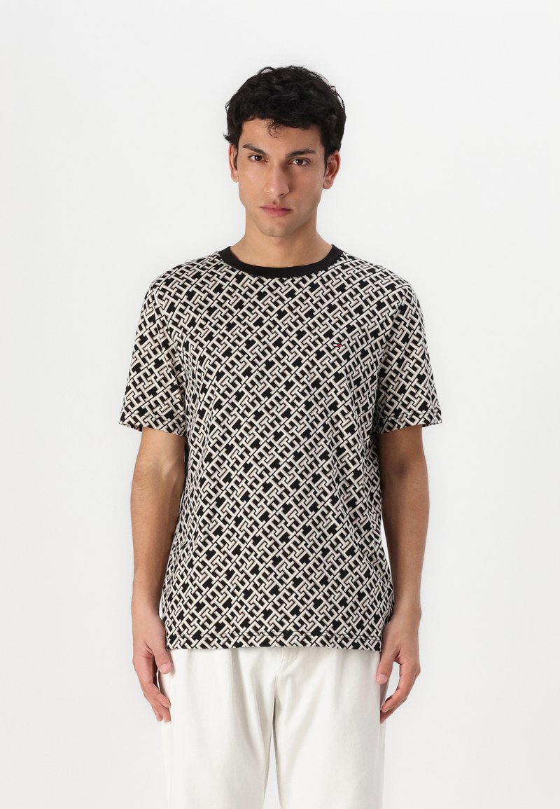 Μακρυμάνικη μπλούζα σε μαύρο και κρέμα, διακοσμημένη με περίπλοκο γεωμετρικό σχέδιο και ριγωτό μαύρο γιακά. Το ύφασμα προσφέρει απαλή υφή.