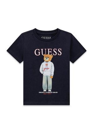 T-shirt noir avec le texte « GUESS » au-dessus d'un ours portant un sweat à capuche blanc et un jean, avec « Original Authentic Brand Est. 1981 » en dessous.