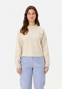 Lichtbeige sweatshirt met een ronde halslijn en doorgezakte schouders, voorzien van lange mouwen en een cropped zoom. Zachte, gladde textuur.