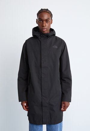 Svart vanntett parka med hette, med glidelås, lange ermer og logo på brystet. Glatt tekstur og knelength design.