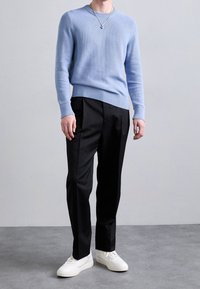 Light blue knit sweater with ribbed hem, paired with black tailored pants and white sneakers. Simple design, smooth texture, and clean lines.