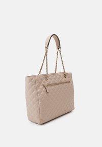 Sac fourre-tout matelassé beige avec des anses en chaîne et des accents en cuir. Dispose d'une poche extérieure zippée et d'un design structuré.