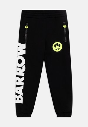 Sorte joggingbukser med elastisk talje, to lommer med lynlås med gule smiley-face lynlåstræk, stor hvid tekst "BARROW" på venstre ben, gul logo på højre.