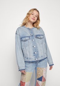 Lichtblauwe denimjacket met een ronde hals, knopen aan de voorkant, twee borstzakken en een licht verkorte zoom. Verweerde details zijn zichtbaar.