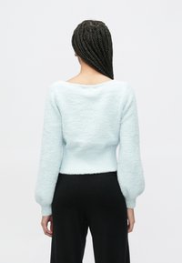 Ανοιχτό μπλε, χνουδωτό πουλόβερ με άνετη εφαρμογή, μακριά μανίκια με φουσκωτό σχέδιο και φαρδύ λαιμό. Μαλακή υφή και κοντό τελείωμα.