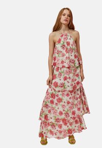 Maxikleid mit floralem Lagen-Design, das rosa und grüne Rosenmuster auf weißem Hintergrund zeigt. Mit Halterneck und fließendem Stoff.