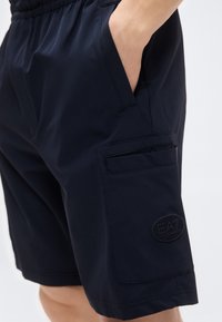 Μπλε ναυτικό cargo σορτς από ελαφρύ ύφασμα, με ελαστική μέση, πλαϊνές τσέπες και λογότυπο στο πόδι.