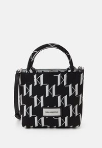 Czarna i biała torba z dzianinowym wzorem przedstawiającym motyw wzajemnie przeplatających się liter 'K'. Zawiera krótkie uchwyty oraz odpinany pasek na ramię.