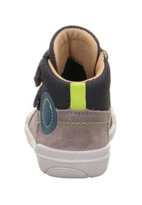 Parte trasera de ante gris de una zapatilla infantil con parte superior de malla azul marino, costuras de acento verde, detalle de parche azul redondo y suela de goma blanca.