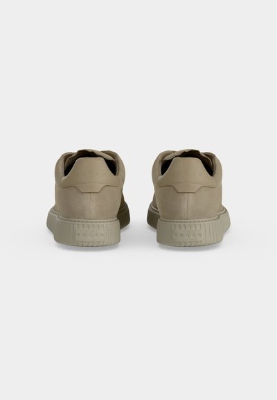 Paire de baskets basses beige vues de dos montrant des semelles texturées et le nom de la marque en relief sur la languette du talon et la semelle.