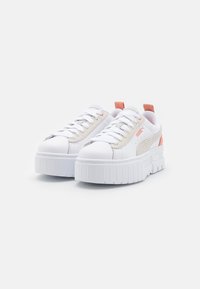 Hvite sneakers med en glatt syntetisk overdel, teksturert beige sidepanel og rosa detaljer. Har en tykk plattformsåle og snøring.