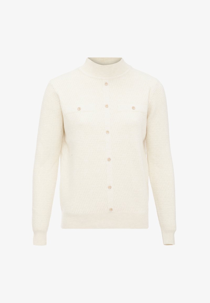 Stickad tröja i krämfärg, med hög krage, knapp-upptill och två bröstfickor med runda knappar. Texturerad tygdesign.
