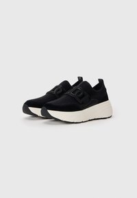 Sorte strikkede sneakers med glatte sorte detaljer, som har en tykk hvit midtsåle og logo-detall. Slip-on design med en teksturert overflate.