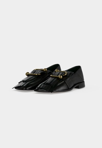 Μαύρα δερμάτινα loafers με κρόσια και μεγάλες διακοσμητικές χρυσές αγκράφες σε λευκό φόντο.