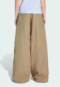 Béžové široké nohavice s voľným strihom, elastickým pásom a zúženými členkami, vyrobené z hladkej, ľahkej látky.