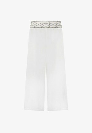 Pantalons larges blancs présentant une taille texturée avec des coutures décoratives et des accents de perles. Fabriqués en tissu léger.