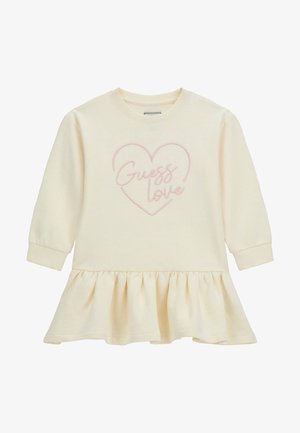 Robe à manches longues couleur crème avec ourlet à volants et contour de cœur rose avec le texte « Guess love » sur la poitrine.
