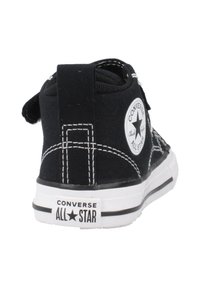Sneaker alta in tela nera con cuciture bianche e suola in gomma. Presenta una toppa con logo circolare sulla caviglia esterna e un anello sul retro.