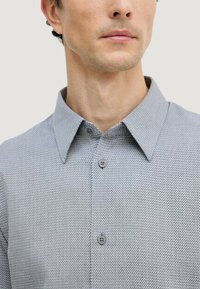 Grau gestreiftes Hemd mit einem Button-Down-Kragen, ausgestattet mit grauen Knöpfen und einem strukturierten Stoff. Nahaufnahme des oberen Vorderbereichs.