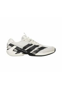 Scarpa da ginnastica bianca con strisce nere e un design sportivo. Parte superiore in rete con suola in gomma, caratterizzata da un dettaglio distintivo sul lato.