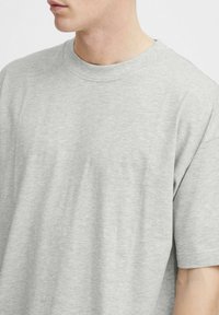 Lysegrå bomulds t-shirt, oversized pasform, rund halsudskæring, korte ærmer, glat tekstur, subtil meleret mønster.