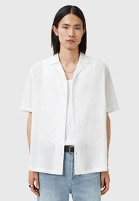 Knap- op kortærmet skjorte i hvidt linen, med en subtil broderet logo på brystet, afslappet pasform og lige søm.