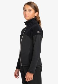 Czarna kurtka na zamek Roxy z teksturową górą, gładką dolną częścią, wysokim kołnierzem i białymi akcentami zamka. Posiada boczne kieszenie.