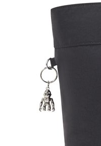 Bolso tote negro de forma cilíndrica con una superficie de tela texturizada, que presenta un charm de robot plateado sujeto a un anillo metálico en el lateral.