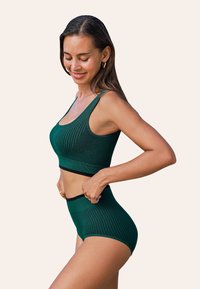 Donkergroen geribbelde sportcrop top en hoog getailleerde slipjes met zwarte accenten, met een aansluitend ontwerp en elastische banden.