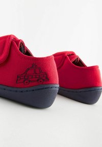 Röda canvas skor med en marinblå gummi sula, med en sydd bildesign på hälen och kardborreband för enkel stängning.