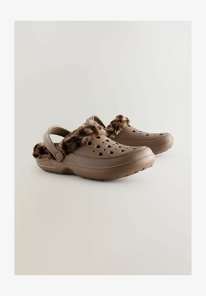 Bruna träskor med ett plyschband i leopardmönstrad fuskpäls, med ventilationshål och en rem baktill för säker passform. Slät, strukturerad yta.