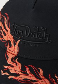 Crna kapa s vezom u crvenoj i narančastoj boji koji prikazuje plamen, s "Von Dutch" logom u crnoj niti, izrađena od tkanine s čvrstom strukturom.