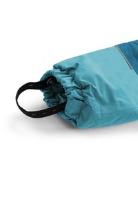 Faltbare Tasche aus tealfarbenem Stoff, mit einem gerafften Öffnungsdesign, schwarzem Tragegurt und Knopfdetails, konzipiert für eine kompakte Aufbewahrung.