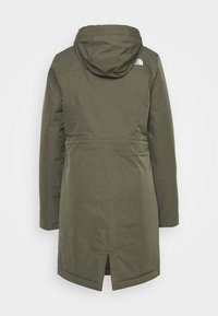 Zielona kurtka z kapturem o gładkiej teksturze i średniej długości. Posiada wentylację z tyłu oraz detal z logo na lewym ramieniu.