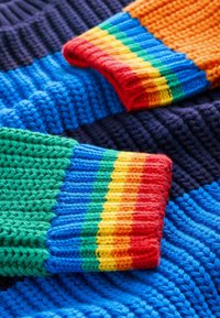 Tessuto lavorato a maglia colorato con vivaci strisce di rosso, arancio, giallo, verde e blu. Trame testurizzate in diverse tonalità.