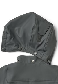 La capucha de la chaqueta impermeable gris presenta botones a presión y un detalle de Velcro, con una textura lisa y ligeramente brillante y detalles fruncidos en la parte trasera.