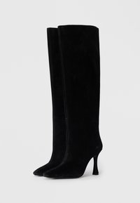 Svarte kne-høye støvler laget av semsket skinn. Har spiss tå og stilettosøyle. Glatt tekstur med et strømlinjeformet, minimalistisk design.