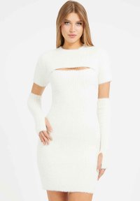 Balta pūkuota megzta suknelė su trumpomis rankovėmis, pjūvio detale prie kaklo ir bepirščiais rankovėmis. Turi prigludusią, aptemptą siluetą.