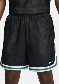 Pantalones cortos de baloncesto negros con un patrón texturizado, cinturilla elástica, dobladillo con rayas verdes y blancas, y un pequeño logo de Nike en el lateral.